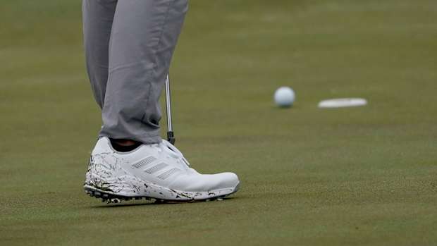 Side view of white adidas golf shoes.